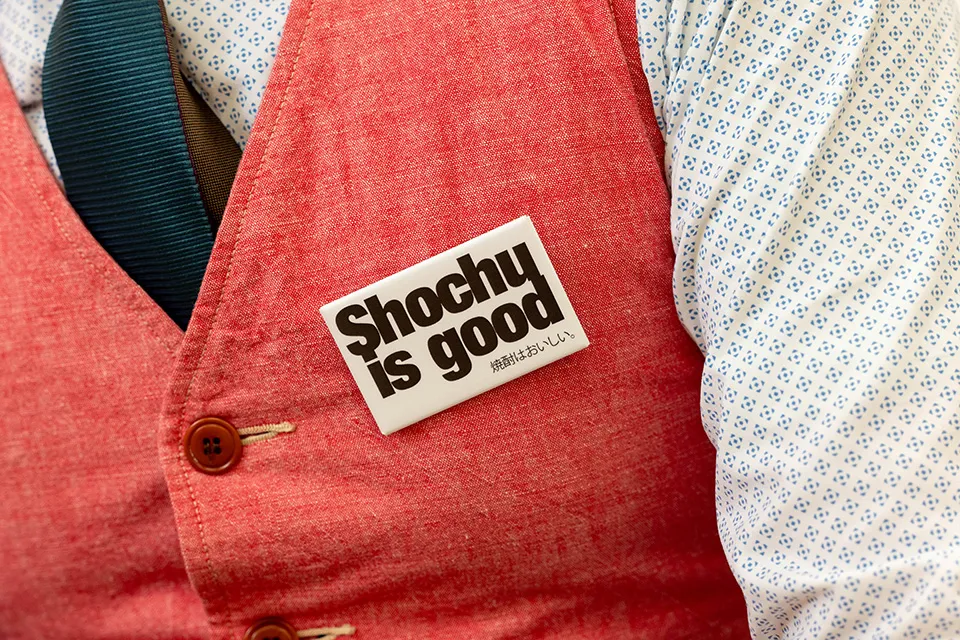 胸元に付けた「Shochu is good（焼酎はおいしい）」の言葉が、焼酎愛を物語っている